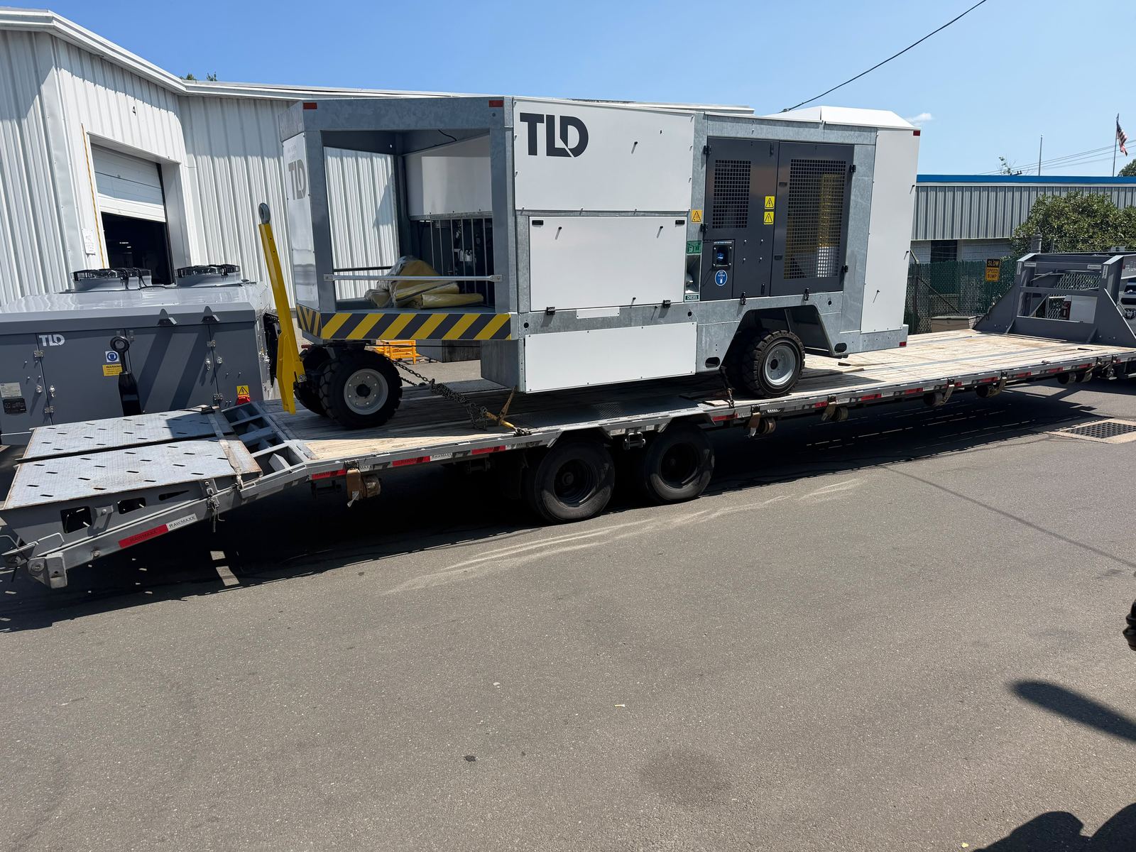 A step deck trailer loaded with aircraft ground support equipment, ramps down
