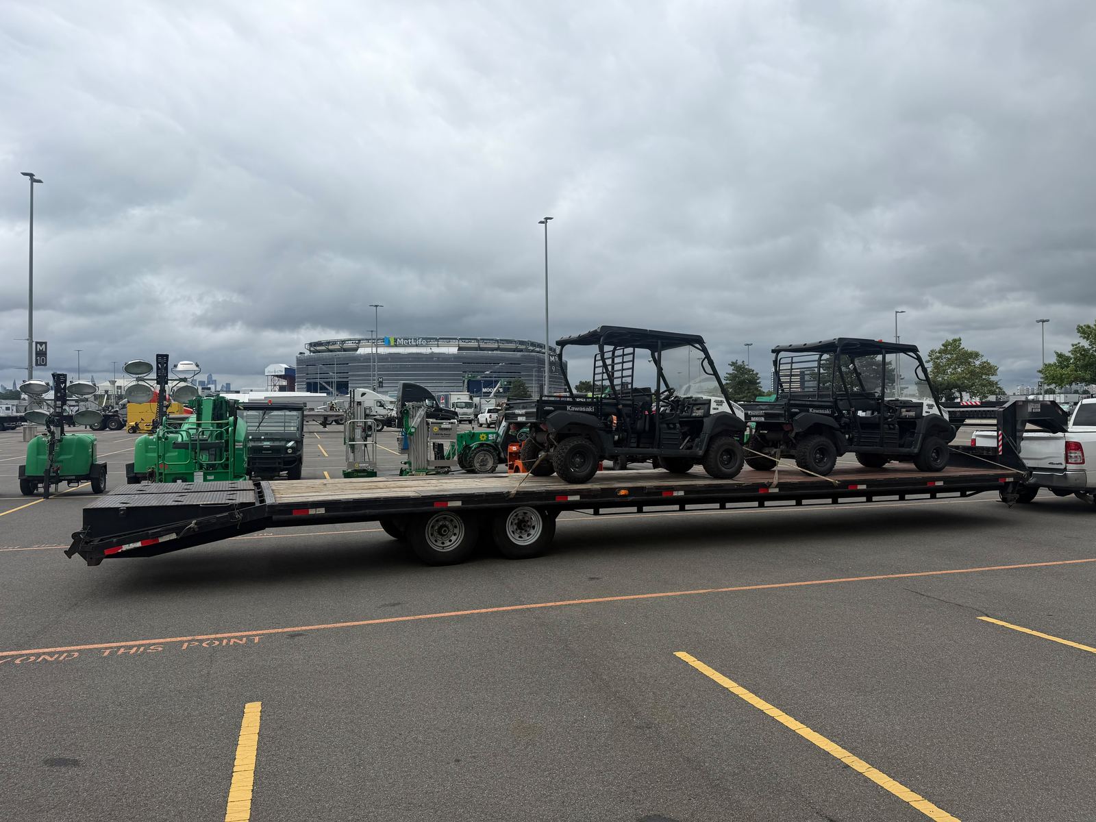 A gooseneck flatbed carrying two utility vehicles, chained and strapped