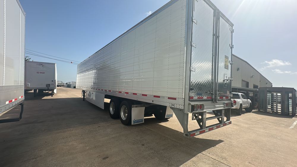 A refrigerated trailer parked at a dock alongside others in the yard